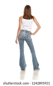 Back View Of Young Pretty Woman Posing In Bell Bottom Jeans On White Background