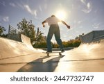 Back view of young skateboarder flies with his board on the ramp of a skate park