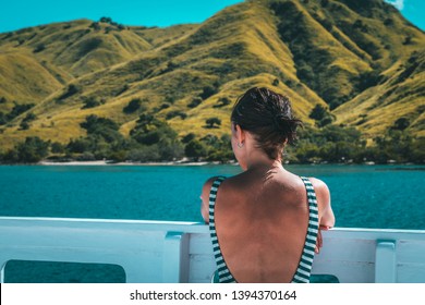 Back View Of Young Solo Traveler Woman Sitting At Yacht, During Komodo Islands Boat Trip.