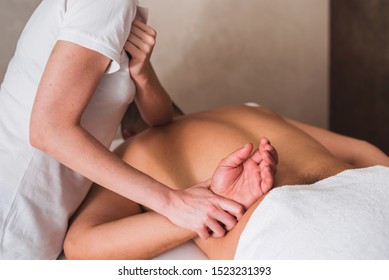 Back view of a young sportman getting a lomi lomi massage in a spa clinic. Closeup picture