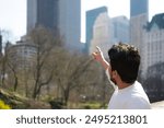 Back view of a young tourist man in new york city, he is pointing out at the skyscrapers