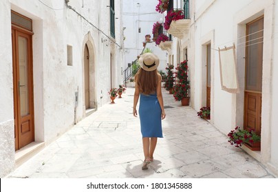 Back view of young tourist woman on ancient street in old town. Travel woman in straw hat and blue dress enjoying vacation in Europe. Tourism and travel concept. - Powered by Shutterstock