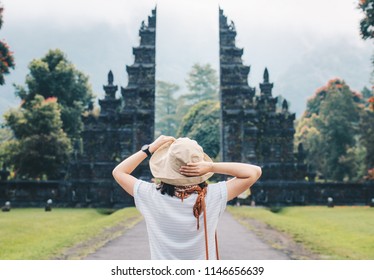 Back view of young tourist women enjoy her holiday in Bali with the view of traditional Hindu gate in Bali island, Indonesia.