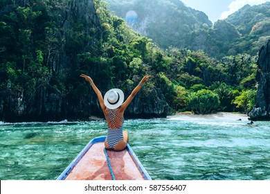 Back view of the young woman in hat relaxing on the boat and looking at the island. Travelling tour in Asia: El Nido, Palawan, Philippines. - Powered by Shutterstock