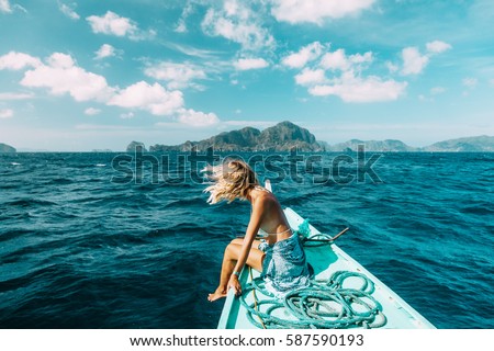 Back view of the young woman relaxing on the boat and looking at the island. Travelling tour in Asia: El Nido, Palawan, Philippines.