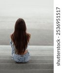 Back view of a young woman sitting on the stairs in urban environment