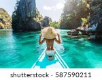 Back view of the young woman in straw hat relaxing on the boat and looking forward into lagoon. Travelling tour in Asia: El Nido, Palawan, Philippines.