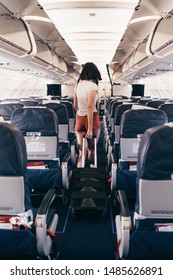 Back View Of Young Woman Walking The Aisle On Plane