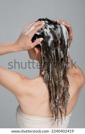back view of young woman washing wet and foamy hair isolated on grey