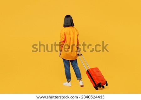 Back view young woman wear summer casual clothes walk go with suitcase bag isolated on plain yellow background. Tourist travel abroad in free spare time rest getaway. Air flight trip journey concept