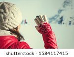 Back view of young woman in a winter clothes and Christmas gloves waving her hand to her friends from group of touristswhile walking in the snowy mountains. 