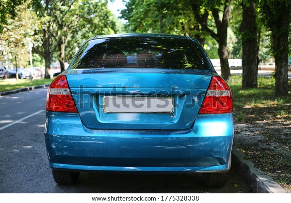 Back window of blue\
car parked on the street in summer sunny day, rear view. Mock-up\
for sticker or decals