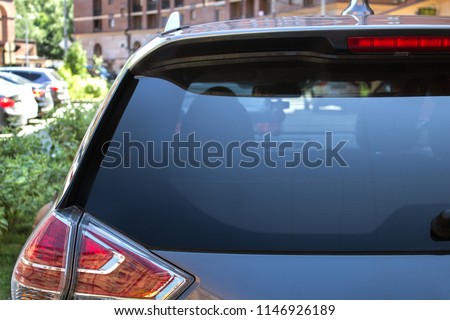 Back window of a car parked on the street in summer sunny day, rear view. Mock-up for sticker or decals