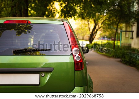 Back window of green car parked on the street in summer sunny day, rear view. Mock-up for sticker or decals