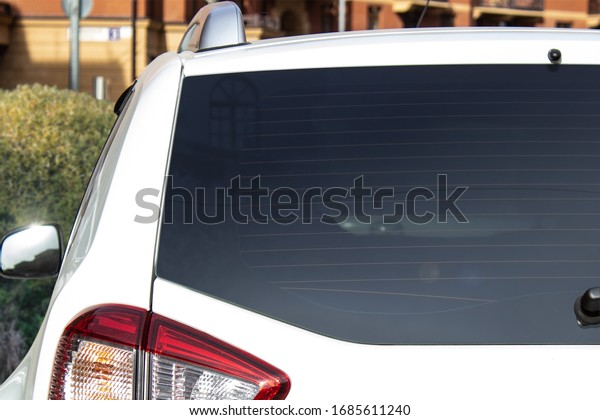 Back window of a white car\
parked on the street near houses, rear view. Mock-up for sticker or\
decals