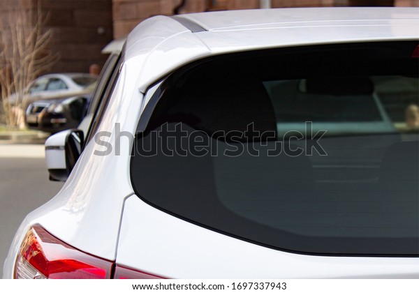 Back window of a white car parked on\
the street, rear view. Mock-up for sticker or\
decals