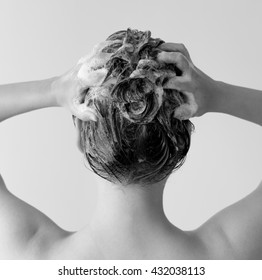 Back Of A Woman In A Shower Shampooing Her Hair, Massaging Her Head Full Of Suds In Black And White.