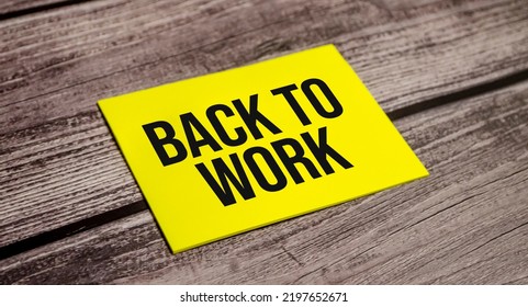 Back To Work Words On Yellow Paper With And Wooden Background