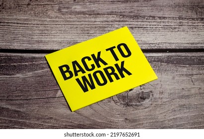 Back To Work Words On Yellow Paper With And Wooden Background