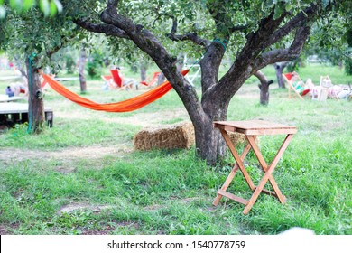 Back Yard With Hammock And Wooden Table For Relaxing. Terrace, Apple Garden In Summer, Wooden Table With Haystack. Wooden Table On Patio On An Autumn Day In Village. Relaxing In Hammock In Garden. 