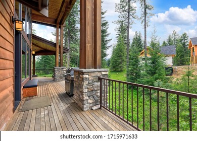 Back yard porch long with stone and metal railing in a beautiful large AMerican home with pine trees forest.
