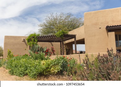 Back Yard Of Stucco, Spanish, Or Santa Fe Style Home. Pergola, Garden And Cacti Visible.