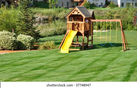 Back Yard Wooden Swing Set On Green Lawn