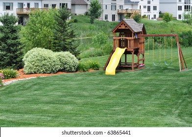 Back Yard Wooden Swing Set On Green Lawn