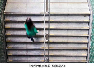 The back of young anonymous woman climbing the stairs. Overhead of grey stairway, urban transportation concept.
