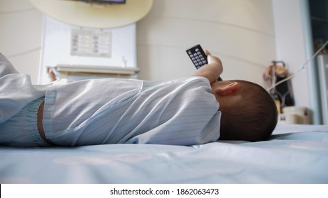 The Back of a young boy laying down and watching TV as he rests 