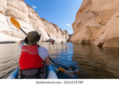 Back of young happy girl kayaking on lake powell with paddle and kayak and life vest on Antelope slot canyon in Arizona during summer - Powered by Shutterstock