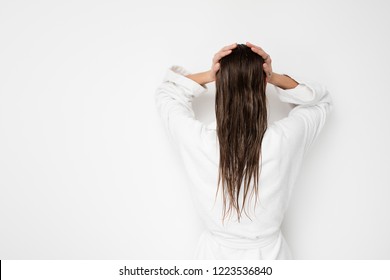 Back Of A Young Woman Showing Her Wet Hair To Camera In Bathrobe On White Background