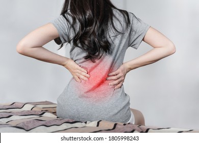 Backache and Lower back pain. Young woman suffering from back pain, on bed after waking up