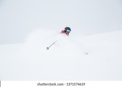 Backcountry skiing in Japan in deep, soft snow. A middle-aged skier turns in powder and gets snow blown into his face.
