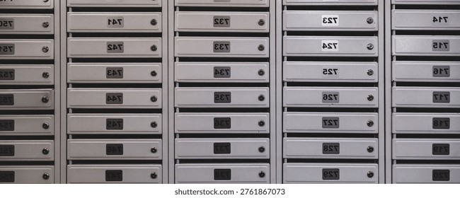 Backdrop of rows of numbered mailbox in modern residential apartment build. Background of white Mailboxes in an apartment residential new building. Urban correspondence concept. Copy text space