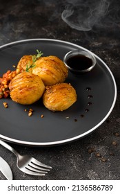 Backed Accordion Potatoes And Vegetables And Sauce In The Dark Plate 