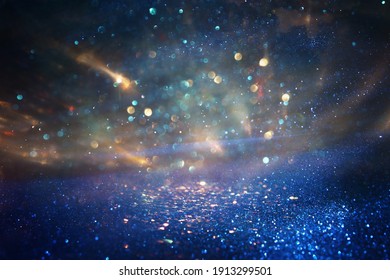 Background Of Abstract Blue, Gold And Black Glitter Lights. Defocused