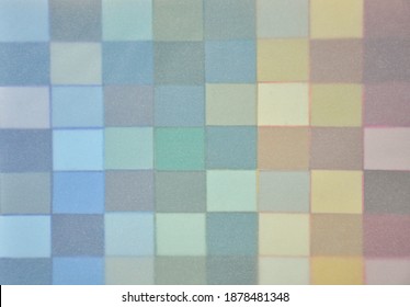 Background abstract pattern. Multi rainbow coloured squares of paper in a geometric grid. Covered with a layer of translucent transparent tracing paper to create a soft blur dreamy effect 