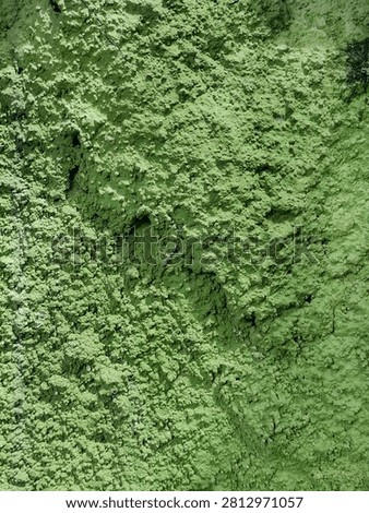 Background of an abstract texture with a rough, cracked, and uneven layer of weathered green plaster. Surface of grunge wall with a pattern of green roughcast texture has natural and artistic appeal.