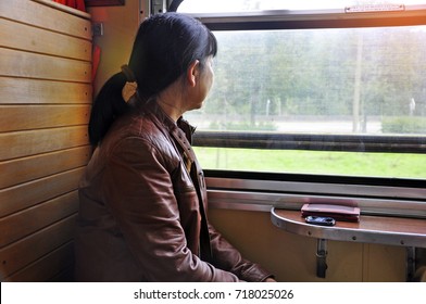 Background Of Asian Woman Sat On The Old Train On Wooden Chair Looked Outside The Window Near By Her Smart Phone With The Sunshine In The Afternoon . 