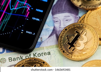 Background with Bitcoin Cryptocurrency coins on South Korea Won banknotes and chart graph on mobile phone. Bitcoin Cryptocurrency concept. South Korea Won Stock Exchange Chart Graph