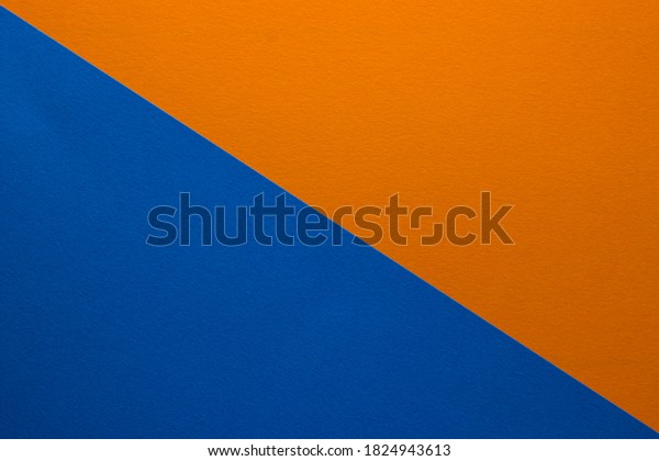 Background of\
blue and orange paper divided diagonally. Sheets of blank orange\
and blue paper with fine texture, close\
up.