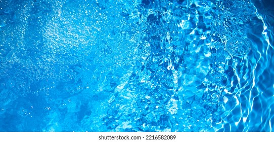 Background of blue water in the pool with small bubbles and splashes. Cooling blue background with clear water. Freshen up after a hot day.