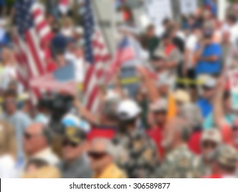 Background blur of crowd at political rally in the United States holding signs and carrying US flags. Great image for upcoming election cycle in 2016 presidential campaigns. Copy space
