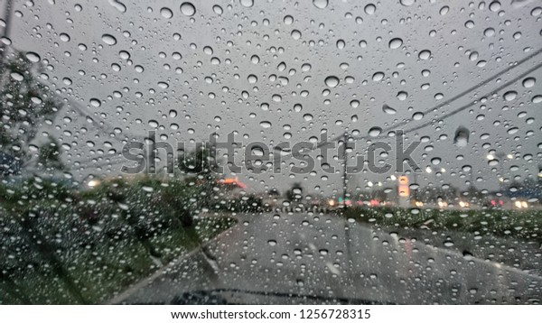 Background is blurred, raindrops on the windscreen to\
car. 