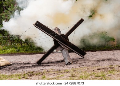 Background. Bomb exploding between the trees neer  Czech hedgehog. Reconstruction of battle from the Second World War.