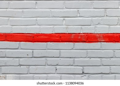 Background of brick wall painted gray. A red line is drawn in the middle of the wall.