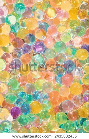 Background of bright multi color transparent gel balls on a sunny day and concept of multitude.