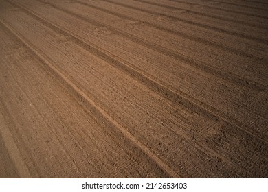 Background of brown earth at high altitude aerial view. Aerial drone view of freshly plowed field ready for seeding and planting in spring. Plowed field in Italy, drone view.