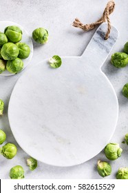 Background with Brussels sprouts and marble cutting board on light gray stone table. Healthy food concept with copy space. Top view.